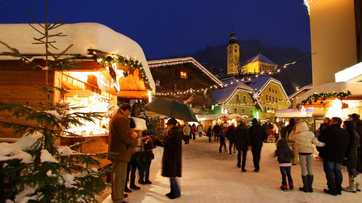 Adventní trh v centru městečka Grossarl s nasvíceným kostelem a stánky s řemeslnými výrobky