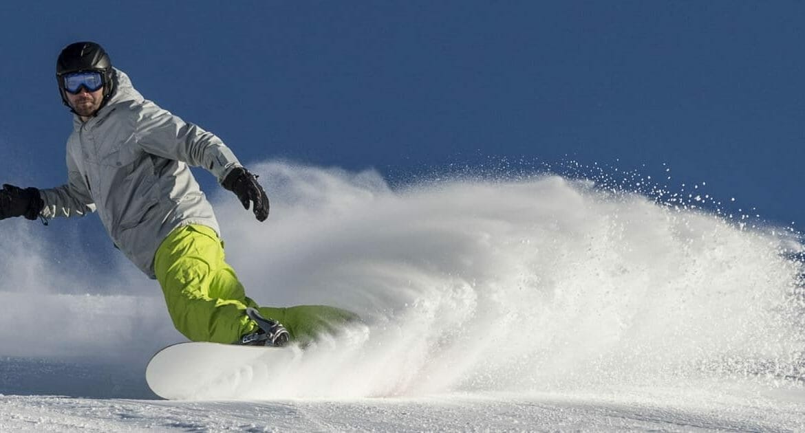 Snowboardista dělá obloučky v prašanu v lyžařské oblasti Almenwelt Lofer