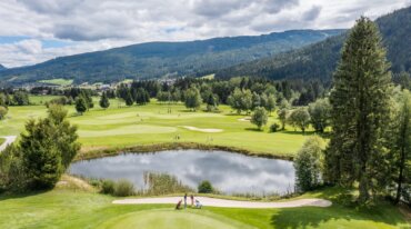 Hráči na 18jamkovém golfovém hřišti v Salcburském Lungau s jezírkem.