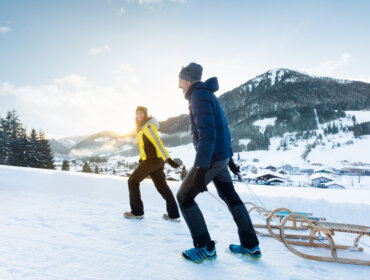 Pár se saněmi v zimní přírodě regionu Tennengau