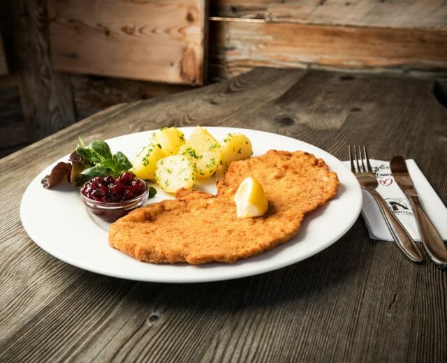 Schnitzel mit Petersilienkartoffel und Preiselbeeren Tradiční řízek s bramborami a petrželkou, to vše doplněné brusinkami. Klasika salcburské kuchyně.