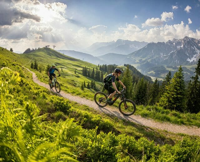 Mountainbike Jízda na horském kole po trase mezi zelenými pastvinami v kopcích regionu Hochkönig