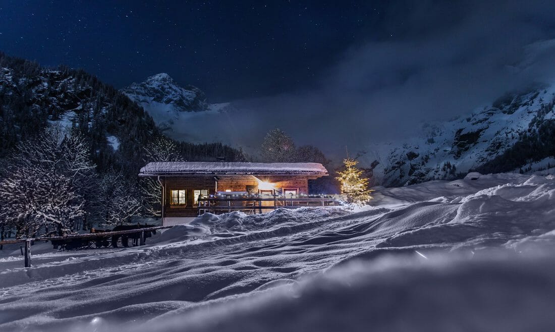 Wengerau Alm, chalupa pod horami pokrytá sněhem a do tmy září jen rozsvíceno za okny