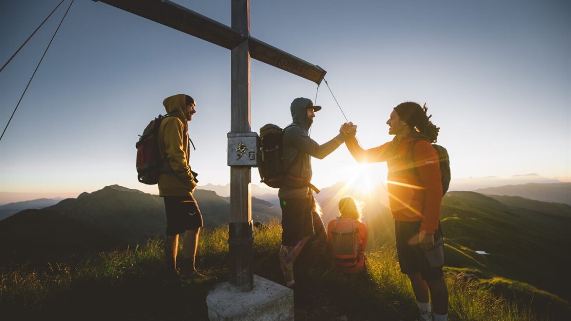 Skupina turistů v horách u vrcholového kříže v Saalbachu Hinterglemmu