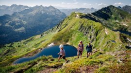 Rodina si užívá jednu z mnoha turistických tras v salcburském Lungau. V pozadí je vidět okolní horská krajina a horské jezero „Twenger Almsee“.
