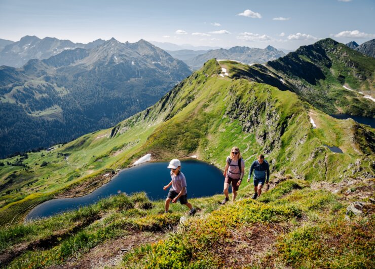 wandern-salzburger-lungau_tauernkrone_©roastmedia Rodina si užívá jednu z mnoha turistických tras v salcburském Lungau. V pozadí je vidět okolní horská krajina a horské jezero „Twenger Almsee“.