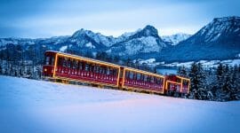 Vánočně vyzdobená zubačka SchafbergBahn jede na horu Schafberg zasněženou krajinou