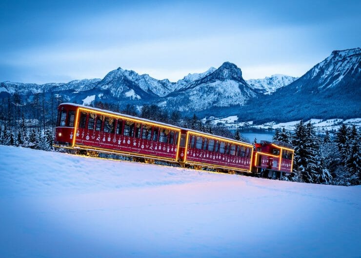 Vánočně vyzdobená zubačka SchafbergBahn jede na horu Schafberg zasněženou krajinou