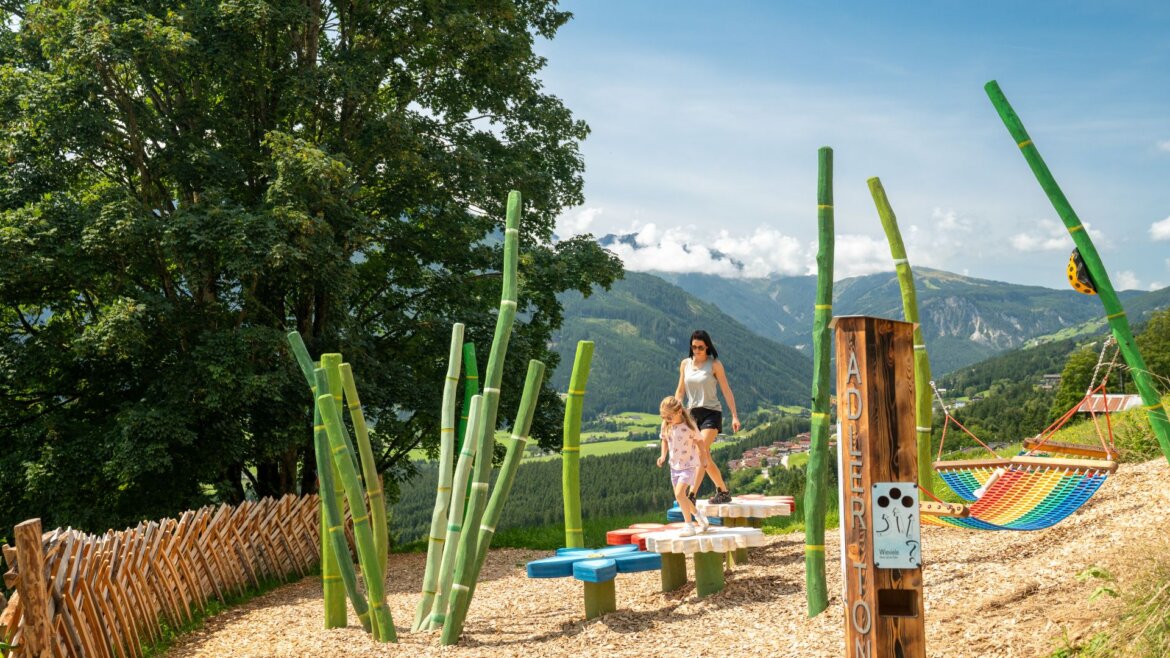 Žena a dítě si hrají na barevném zařízení u houpací sítě ve Wildkogel Aréně Neukirchen Bramberg.