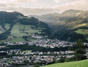 Městečko St. Johann v zeleném horském údolí pod částečně zataženou oblohou v Salcbursku.