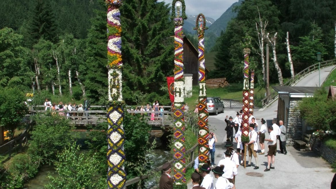 Procesí s vysokými pilíři zdobenými květinami prochází obcemi v Salcburském Lungau