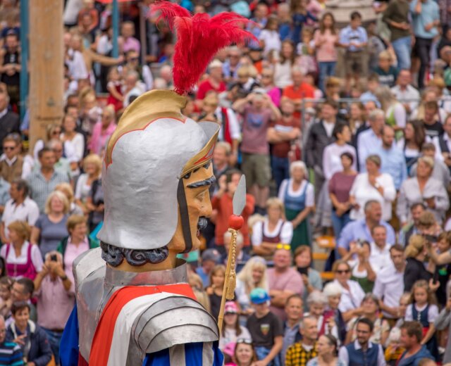 Velká postava patrona Lungau s přilbou stojí před lidmi na přehlídce Samsonů