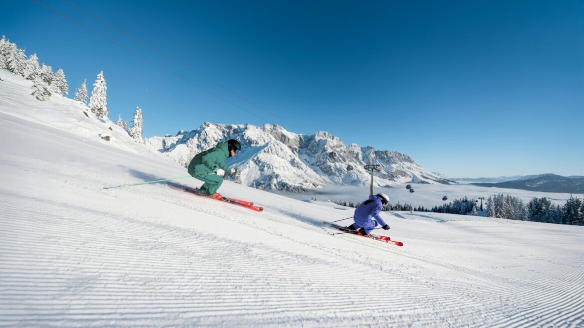 Lyžaři na široké upravené sjezdovce v regionu Hochkönig
