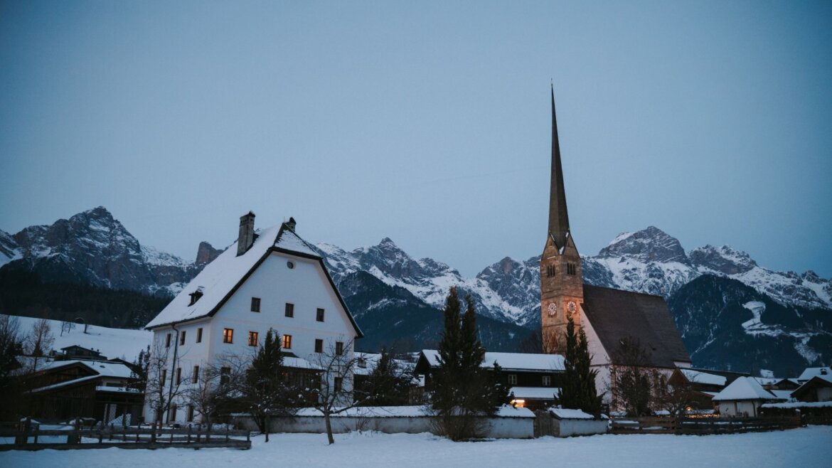 Zasněžená obec s kostelem a horami v regionu Hochkönig (Zvětšený pohled)