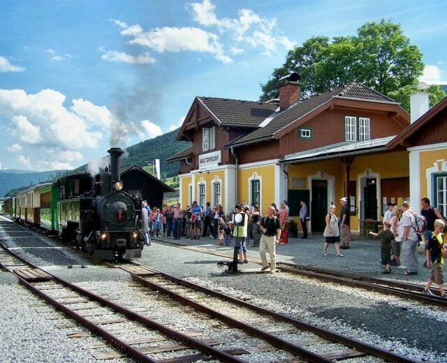 da52318d-ffc4-466b-8155-d6e1fd22439e_taurachbahn_ Historický vlak na železnici Taurachbahn v zastávce Mauterndorf v Salcburském Lungau. Odtud vyráží do obce St. Andrä.