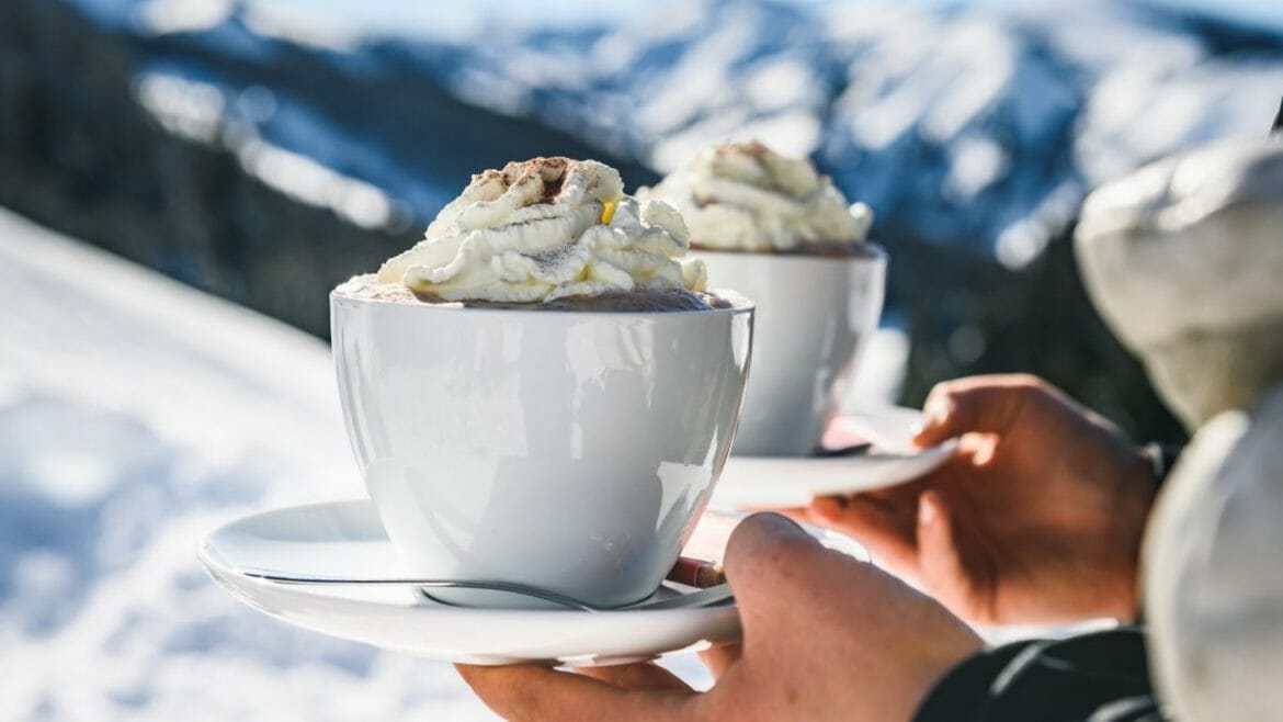 Šlehačka na horké čokoládě v bílém hrnku připomíná alpské vrcholy