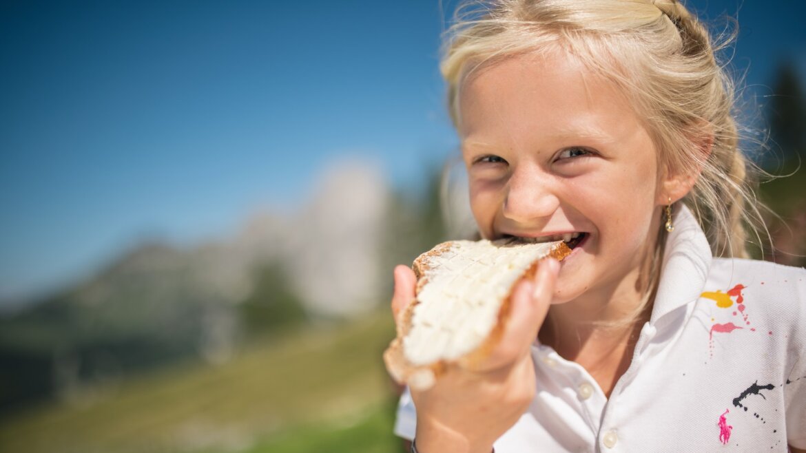Dítě si pochutnává na chlebu na horské louce ve Filzmoos