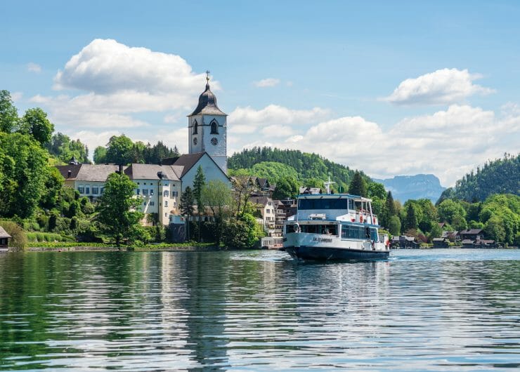 Pohled na městečko St. Wolfgang okolo kterého pluje po jezeře Wolfgangsee loď na plavbě 