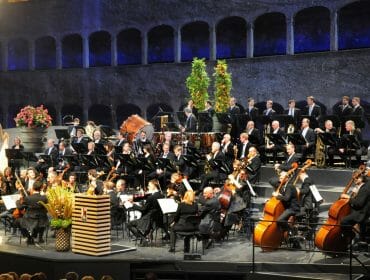 Felsenreitschule Orchestr na zahajovacím koncertu Salcburského festivalu ve Skalní jízdárně, která byla vytesána do Mnišské hory a dodnes fascinuje svým jevištěm, které lemují kamenné arkády. Se svou kapacitou 1437 míst k sezení patří k nejvýznamnějším salcburským scénám, kde se uvádějí opery, činohry a koncerty.