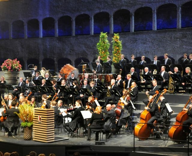 Felsenreitschule Orchestr na zahajovacím koncertu Salcburského festivalu ve Skalní jízdárně, která byla vytesána do Mnišské hory a dodnes fascinuje svým jevištěm, které lemují kamenné arkády. Se svou kapacitou 1437 míst k sezení patří k nejvýznamnějším salcburským scénám, kde se uvádějí opery, činohry a koncerty.