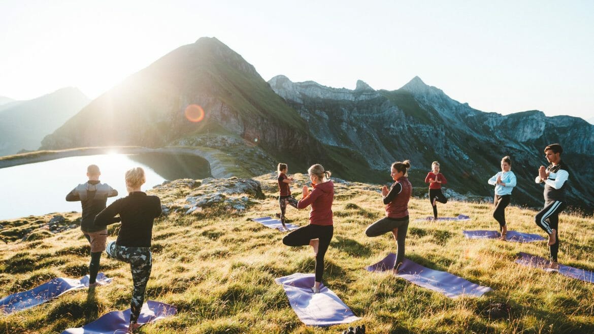 Ženy cvičí jógu u horského jezera v Obertauern