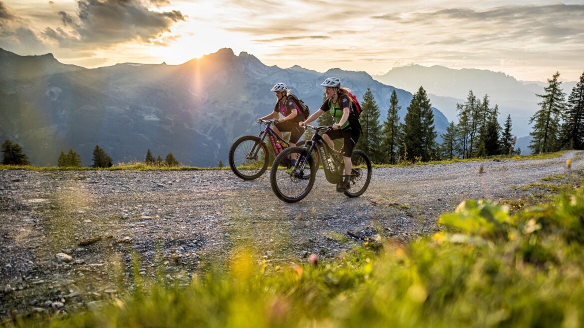 V Großarltalu je 16 tras pro horská kola s převýšením až 1000 metrů © TVB Grossarltal, Andreas Meyer Dva lidé jedou na horských kolech po štěrkové cestě v Grossarltal v Salcbursku v létě při západu slunce. (Zvětšený pohled)