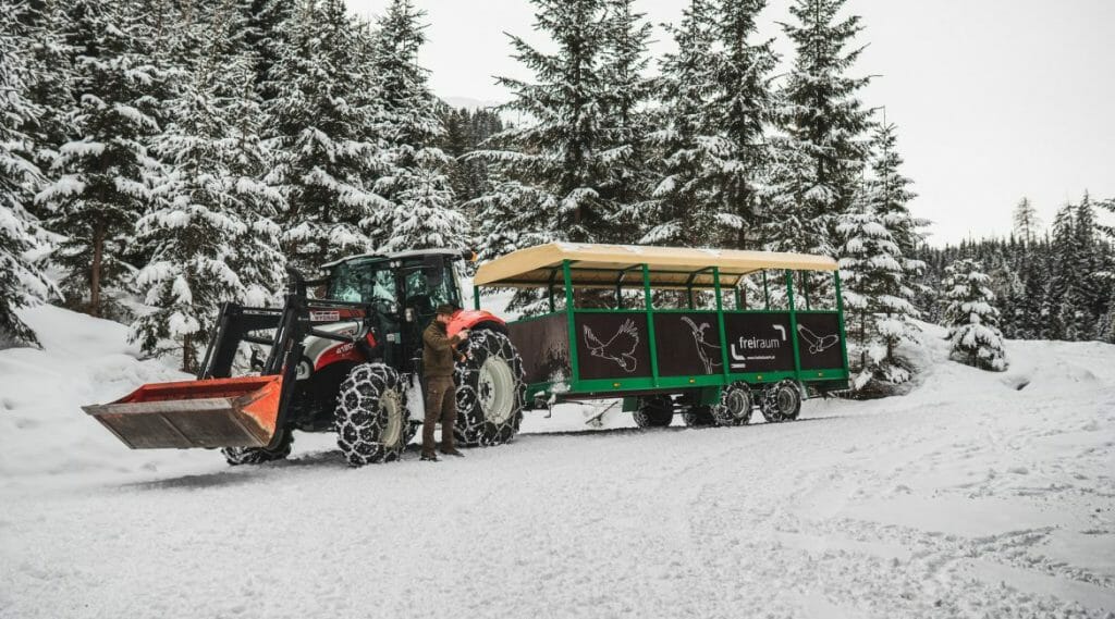 Turisté se pohodlně dostanou do zasněžených oblastí v lese ve speciálním krytém přívěsu za traktorem, který musí mít na kolech sněhové řetězy