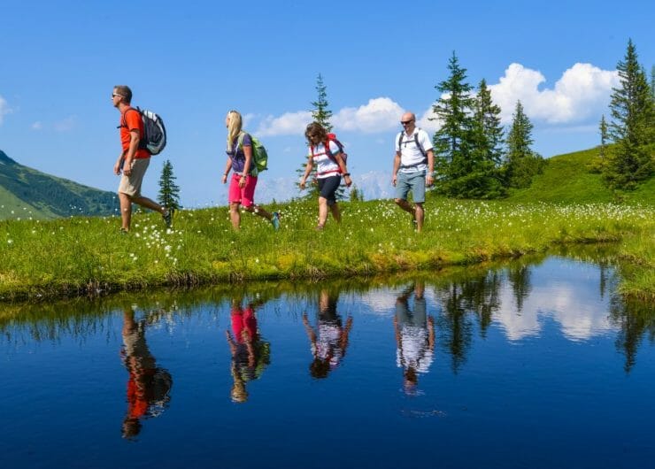 Pěší túra v Hochkönigu okolo po hebkých zelených pastvinách, okolo jezera, kde se na hladině odráží modré nebe