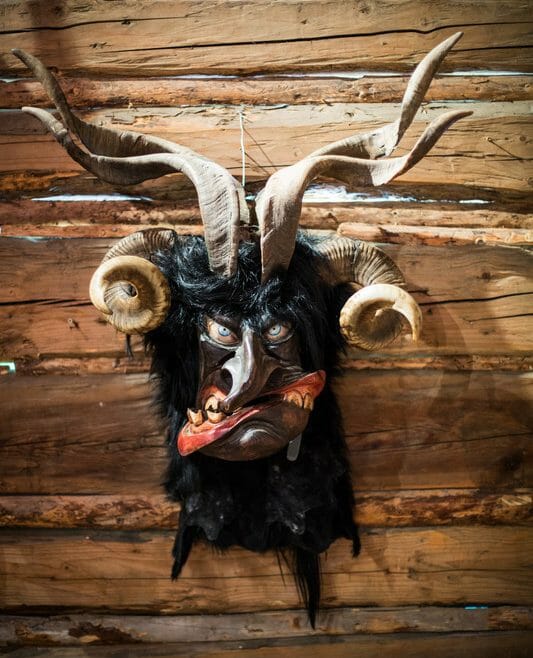 Vyřezávaná maska děsivého čerta Krampuse s vyplazeným jazykem a zvířecími rohy může sloužit i jako svérázná dekorace k zavěšení na stěnu