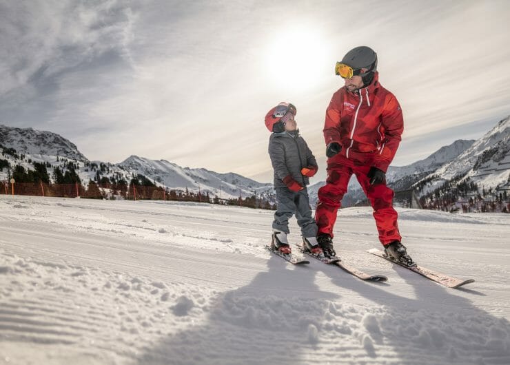Instruktor lyžařské školy na svahu se svým malým svěřencem, který se v Salcbursku učí své první obloučky na lyžích