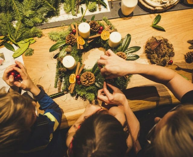 Domácí výroba adventního věnce z přírodnin jako je jehličí, šišky, skořice a sušené plátky citrusů