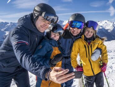 dsc04297.1920×0 Rodina v lyžařské výstroji se usmívá a pořizuje si selfie na Zimní rodinná dovolená Wildkogel Arena s modrou oblohou.