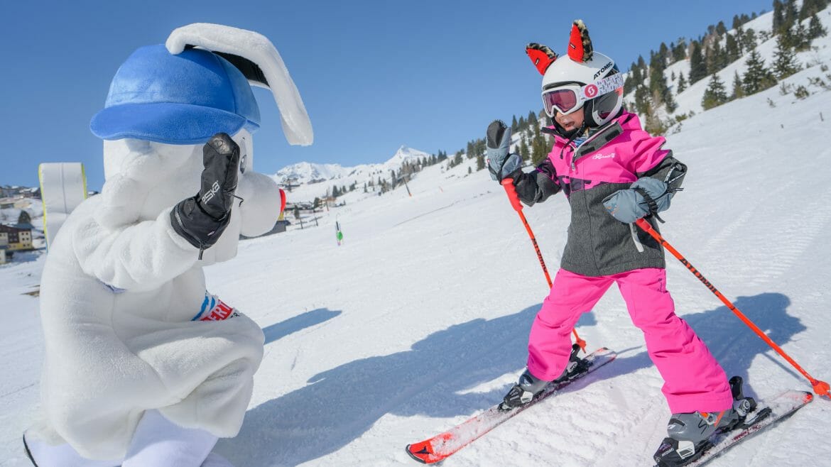 Malá lyžařka si po svém úspěšném sjezdu může plácnout s veselým králíkem, který je jedním z maskotů lyžařské oblasti Obertauern