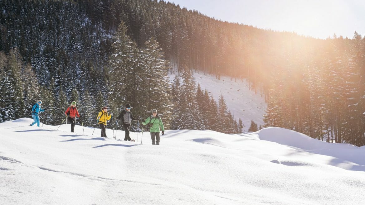 Trojice turistů kráčí hlubokým sněhem v Raurisertalu