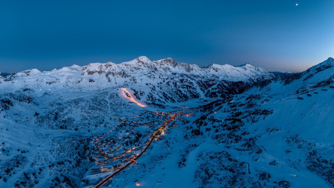 Obertauern se spoustou sněhu za soumraku, zářící světla ze sjezdovek na nočním lyžování