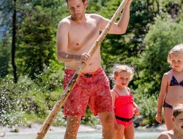 Muž a tři děti si hrají v řece - ideální pro letní rodinná dovolená Salcburský Saalachtal.