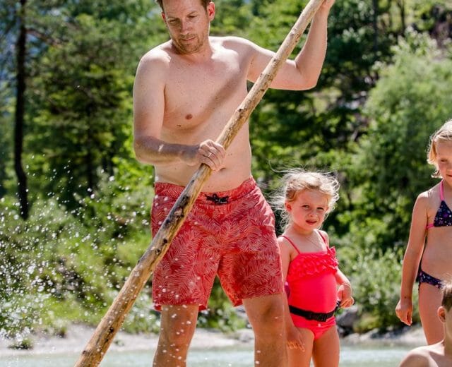 Muž a tři děti si hrají v řece - ideální pro letní rodinná dovolená Salcburský Saalachtal.