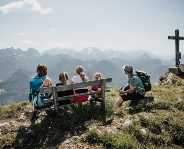 Rodina na výletě odpočívá na lavičce v oblasti Almenwelt Lofer v Salcburském Saalachtalu