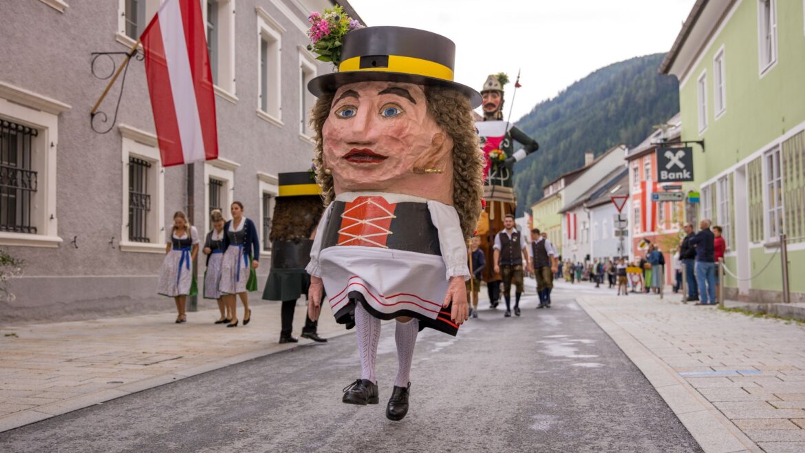 Postava ve velkém kostýmu s velkou maskou na hlavě vede průvod s obrem Samsonem v obci Tamsweg v Salcburském Lungau
