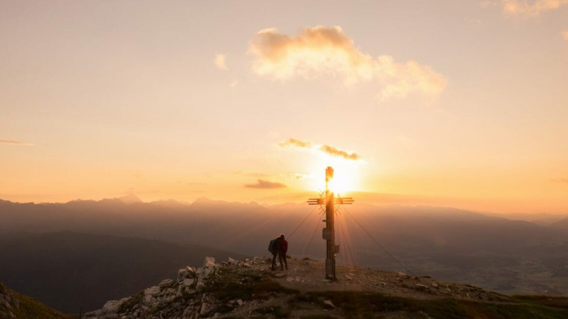 Východ slunce na hoře Speiereck v Salcburském Lungau u vrcholového křížku má magickou atmosféru