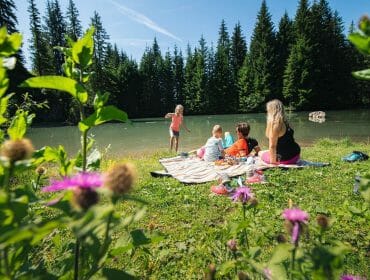 Rodinný piknik na rozkvetlé louce u malebného horského jezera ve Filzmoos
