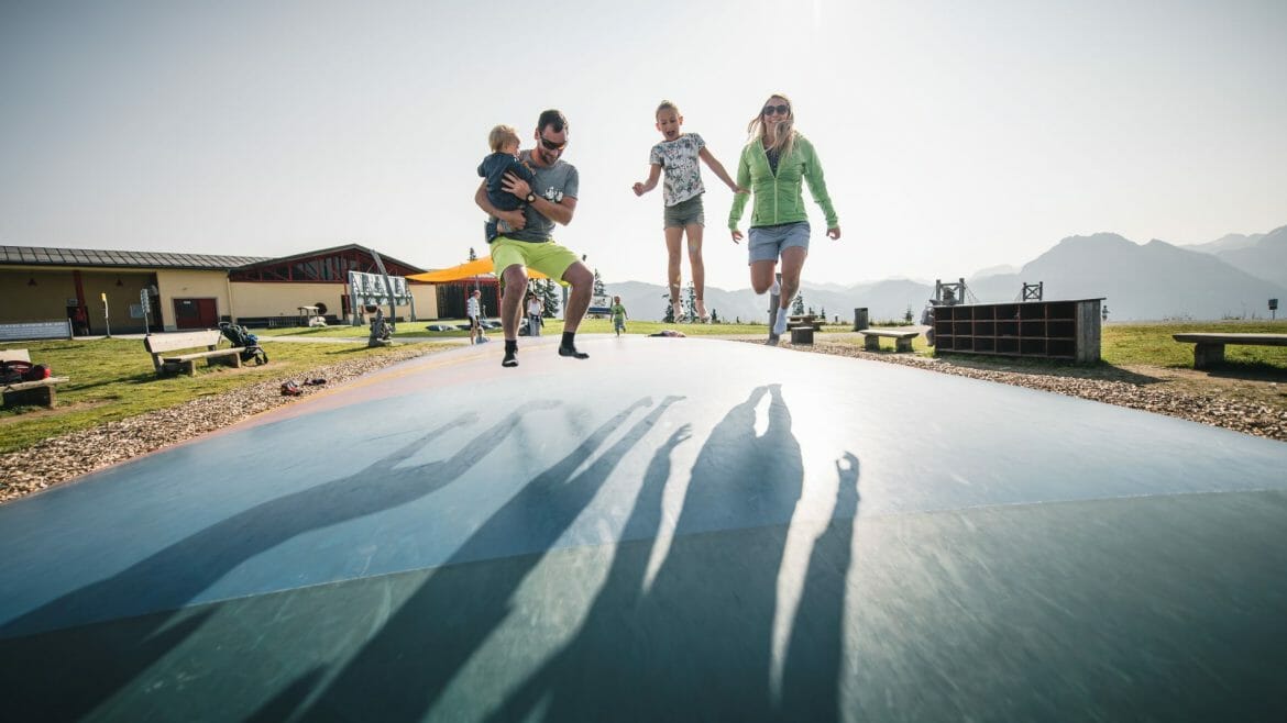 Rodina s dětmi skáče na velké vzduchové trampolíně na jedné ze zážitkových hor v Salcburském sportovním světě