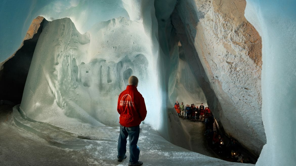 Největší ledovou jeskyní světa ve Werfenu prochází turisté oblečení v zimních bundách a čepicích v doprovodu průvodce