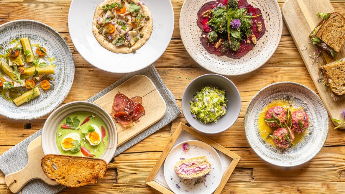 Různorodé barevné obložené talíře na dřevěném stole, inspirované bylinky Hochkönig a bylinkové salaše.