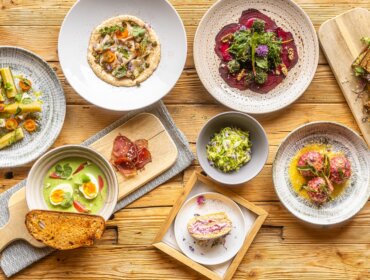 Různorodé barevné obložené talíře na dřevěném stole, inspirované bylinky Hochkönig a bylinkové salaše.