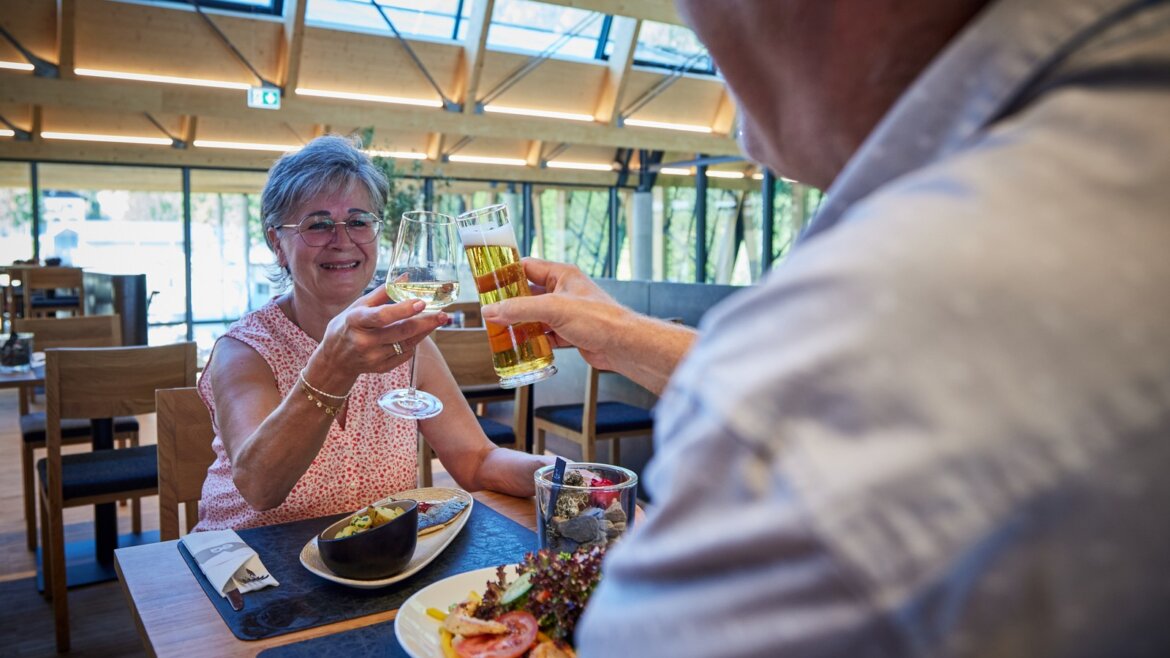 Skvělá gastronomie a příjemné posezení v EQ © Salzburg AG Tourismus GmbH Dva lidé cinkali skleničkami v restauraci u lanovky Zubačka Schafbergbahn, usmívali se a užívali si společné jídlo. (Zvětšený pohled)