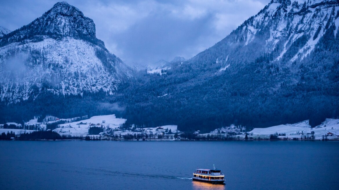 Zasněžené jezero Wolfgangsee brázdí loď