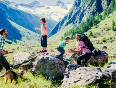 Rodina s dětmi na výletě v horách, kde mohou děti dovádět na velkých kamenech