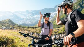 Dva cyklisté si povídají během výletu na horských kolech v alpské krajině v závěru údolí Krimmler Achental