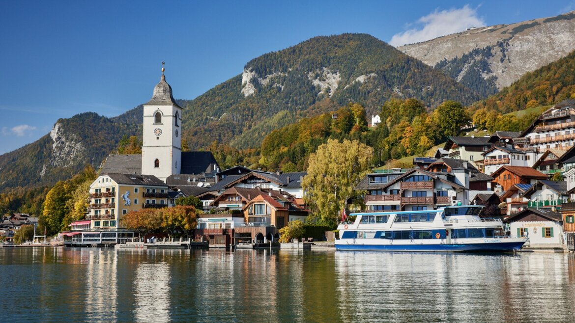Malebný St. Wolfgang u jezera s barevnými budovami, kostelní věží a lodí na jezeře Wolfgangsee (Zvětšený pohled)